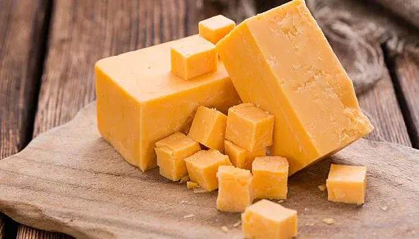 Portion of Cheddar (detailed close-up shot) on vintage wooden background Portion of Cheddar (detailed close-up shot) on vintage wooden background